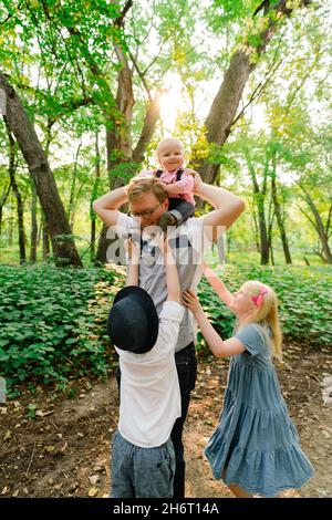 Ein Vater und seine drei Kinder spielen zusammen im Wald Stockfoto