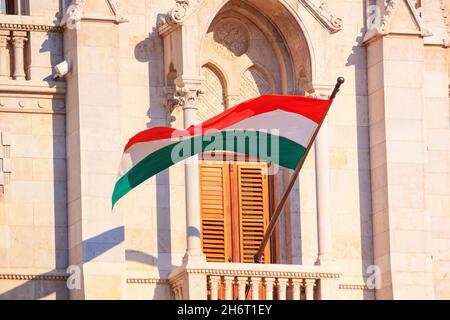 Flagge Ungarns winkt im Wind auf dem ungarischen Parlamentsgebäude in Budapest, Nahaufnahme am sonnigen Tag, Ungarn Stockfoto