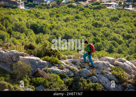 Junger Mann geht bei Sonnenaufgang durch die felsige Landschaft, Calpe, Costa Blanca, Spanien Stockfoto