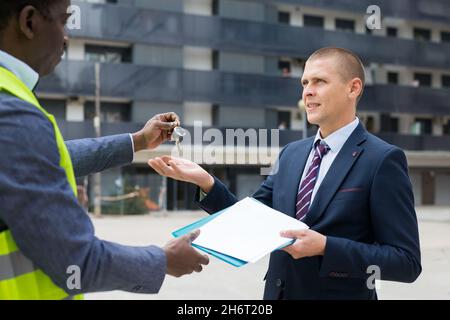 Ingenieur, der den Menschen Schlüssel für eine neue Wohnung gab Stockfoto