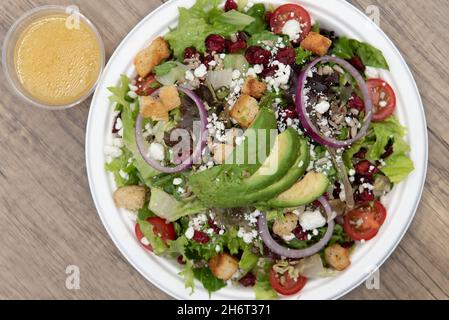 Blick von oben auf gemischte Gemüsesalat mit Gemüse, Zwiebeln und Avocado-Scheiben, die hoch auf dem Teller stapelten. Stockfoto