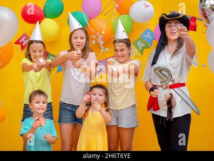 Kinder und Pirat auf der Geburtstagsfeier auf gelbem Hintergrund Stockfoto