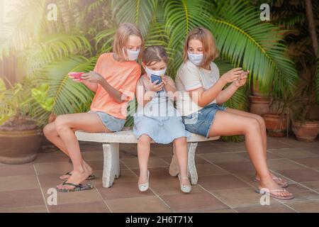 Kinder spielen Gadgets auf der Bank. Mädchen verbringen Zeit miteinander Stockfoto