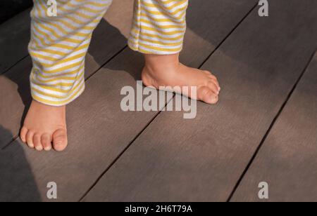 Die Füße des Babys machen ihre ersten Schritte. Babyfüße auf einem hölzernen Hintergrund. Stockfoto