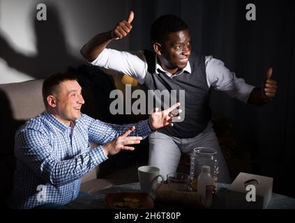 Zwei aufgeregte männliche interracial Freunde beobachten Fußballspiel Stockfoto