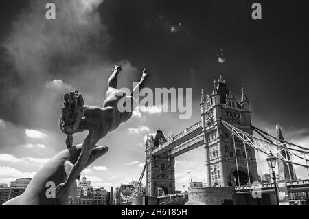 LONDON, VEREINIGTES KÖNIGREICH - 30. Jun 2015: Eine Graustufenaufnahme der Stadtskulpturen und der Tower Bridge im Hintergrund in London, Vereinigtes Königreich Stockfoto