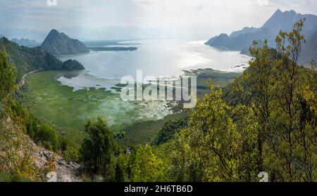 Blick von einer kurvenreichen Bergstraße nicht lange nach Sonnenaufgang im Frühherbst, da Sonnenlicht die Oberfläche des Nockenwassers reflektiert. Stockfoto