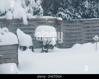 Starker Schneefall. Gartenmöbel sind mit viel Schnee, Saison- oder Wetterkonzept bedeckt Stockfoto