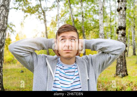 Der junge Mann schließt die Ohren in den Fores Stockfoto