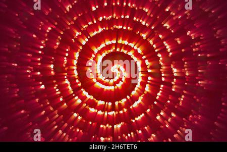Abstrakter fraktaler roter Hintergrund mit sich kreuzenden Kreisen. Rote Strahlen und Lichter fallen in einen runden Trichter Stockfoto