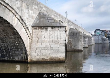 190 Meter lange, gewölbte Steinfußbrücke Sint Servaasbrug (oder St. Servatius-Brücke) über die Maas in Maastricht. Wyck Bezirk im Hintergrund Stockfoto