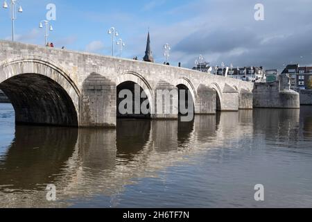 190 Meter lange, gewölbte Steinfußbrücke Sint Servaasbrug (oder St. Servatius-Brücke) über die Maas in Maastricht. Wyck Bezirk im Hintergrund Stockfoto