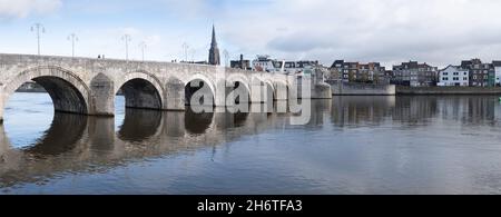 190 Meter lange, gewölbte Steinfußbrücke Sint Servaasbrug (oder St. Servatius-Brücke) über die Maas in Maastricht. Wyck Bezirk im Hintergrund Stockfoto