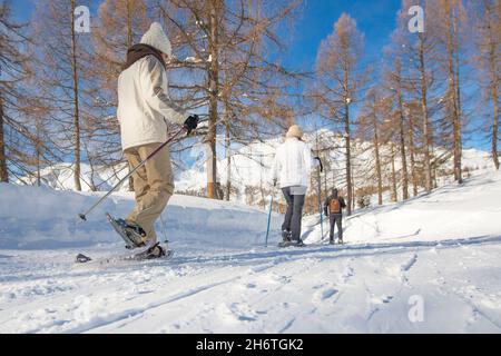 Gehen Sie mit Schneeschuhen auf ausgetretenen Spuren im Schnee Stockfoto
