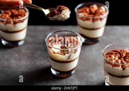Köstliches traditionelles Tiramisu-Dessert in kleinen Glasbechern auf Steinplatten. Das schwaches Bild zeigt Textur und Schichten aus dem Winkel mit Hello Stockfoto