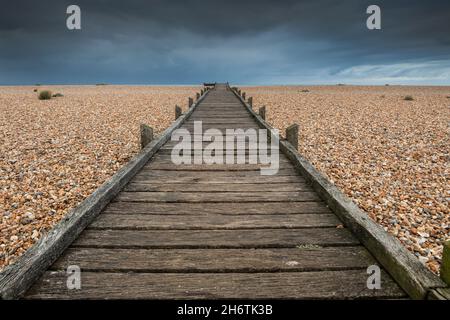 Ein Holzsteg an einem Kiesstrand in Lydd-on-Sea, Kent. Stockfoto