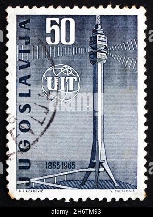 JUGOSLAWIEN - UM 1965: Eine in Jugoslawien gedruckte Marke zeigt das ITU-Emblem und den Fernsehturm, 100 Jahre, um 1965 Stockfoto