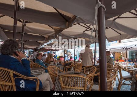 Die Gäste entspannen sich auf der überdachten Außenterrasse eines Restaurants auf der hauptplatz. Capri, Insel Capri, Italien. Stockfoto