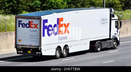 Seiten- und Rückansicht von FedEx Express, einer American Courier Post & Mail-Marke mit Firmenlogo auf lkw-LKW und Anhänger auf der britischen Autobahn Stockfoto