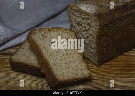 Brot aus braunem, biologischem Roggenbrot auf schwarzem Hintergrund. Zwei Scheiben Brotscheiben. Für Text platzieren. Banner für ein Designprojekt. Stockfoto