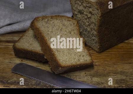 Brot aus braunem, biologischem Roggenbrot auf schwarzem Hintergrund. Zwei Scheiben Brotscheiben. Für Text platzieren. Banner für ein Designprojekt. Stockfoto