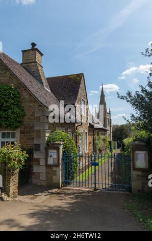 Lane im Dorf Great Cransley mit dem Kirchturm der St. Andrew Kirche in der Ferne; Northamptonshire, Großbritannien Stockfoto