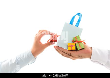 Abgeschnittene Ansicht eines Mannes, der eine Einkaufstasche in der Nähe einer weiblichen Hand hält, mit einer winzigen Geschenkbox, die auf Weiß isoliert ist Stockfoto