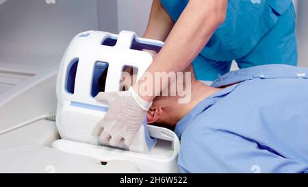Nahaufnahme eines Arztes, der einen tc-Scanner einführt, um eine Hirnröntgenaufnahme an einem jungen Patienten durchzuführen Stockfoto