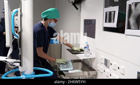 Nahaufnahme eines Arztes oder einer Krankenschwester mit einer Tastatur in einem Operationssaal, mehreren Röntgenstrahlen an der Wand und einem Monitor neben dem Monitor. Stockfoto