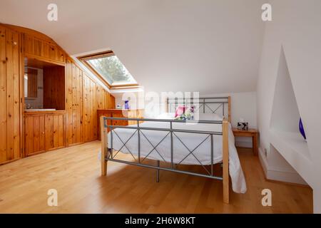 Cambridge, England - August 21 2019: Schlafzimmer im Dachgeschoss in viktorianischem Haus mit Holzpaneelen und Dachfenster Stockfoto