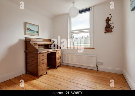 Cambridge, England - August 21 2019: Spärlich eingerichtetes Zimmer im viktorianischen britischen Haus mit traditionellem Holzbüro neben dem Fenster. Stockfoto