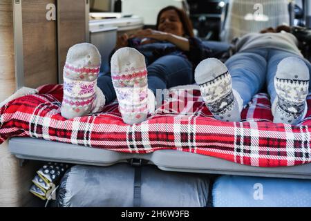 Reife Frauen schlafen im Mini-Van Camper tragen warme Weihnachtssocken - Fokus auf Füße Stockfoto