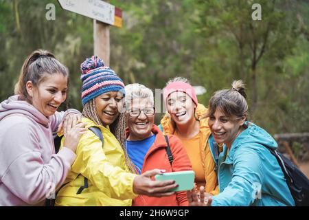 Multirassische Freundinnen, die Spaß beim Selfie haben, während des Trekkingtages in den Wald - Fokus auf afrikanisches Frauengesicht Stockfoto