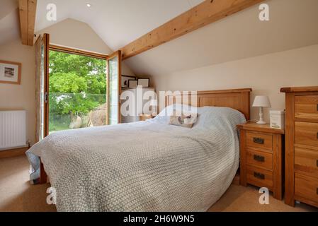 Hargrave, Suffolk, England - Juni 10 2020: Traditionelles englisches Landhaus-Schlafzimmer mit freiliegenden Balken, Kiefernmöbeln und offenen Balkontüren Stockfoto