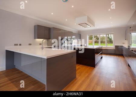 Clavering, England - April 6 2020: Neues Heim Luxus Küche Zimmer Interieur mit, glänzend grauen Einheiten, umfassende Palette von Einbaugeräten Stockfoto