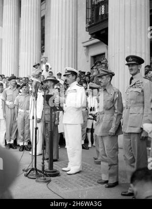 LOUIS MOUNTBATTEN, 1. Earl Mountbatten aus Burma (1900-1979) Offizier der Royal Navy und Staatsmann hielt im Januar 1945 nach der japanischen Kapitulation eine Rede im Stadtgebäude von Singapur. Rechts von ihm ist General William Slim in einem Schlampenhut, links von ihm sind Generalleutnant Wheeler der US-Armee und die große Figur des Air Chief Marshal Sir Keith Park, Stockfoto