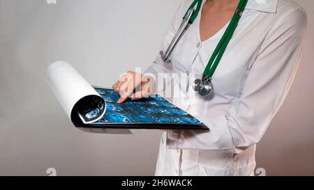 Nahaufnahme einer Ärztin mit einem Stethoskop im Hals, bei der die Diagnose einer Hirnröntgenaufnahme einer Patientin gestellt wird. Stockfoto