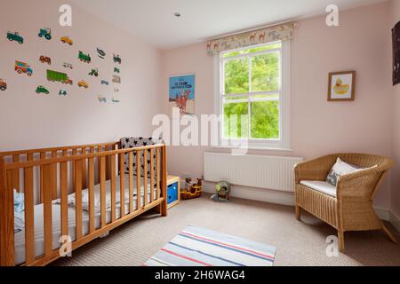 Cambridge, England - August 15 2019: Kinderzimmer im Haus aus britischer viktorianischer Zeit mit Kinderbett, Spielzeug und Korbsessel Stockfoto