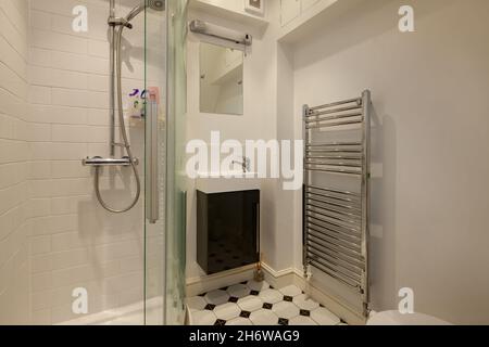 Cambridge, England - August 15 2019: Duschbad mit Glasscheibe und gefliester Kabine, Handtuchhalter und Waschbecken Stockfoto