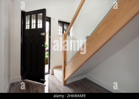 Cambridge, England - Juli 31 2019: Eingangshalle zum renovierten leerstehenden Haus mit offener Tür, Eichentreppe und gefliestem Keramikboden. Stockfoto