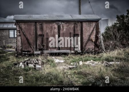 Holzschuppiger rustikaler klassischer alter alter alter Eisenbahnwagen in einem launischen und dunklen filmischen Stil, aufgenommen am Strand von Dungeness 14. vom November 2021 Stockfoto