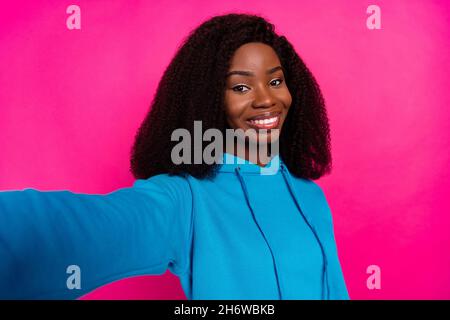 Foto von beeindruckt süßen dunklen Haut Dame tragen blauen Hoodie tacking Selfie lächelnd isoliert rosa Farbe Hintergrund Stockfoto