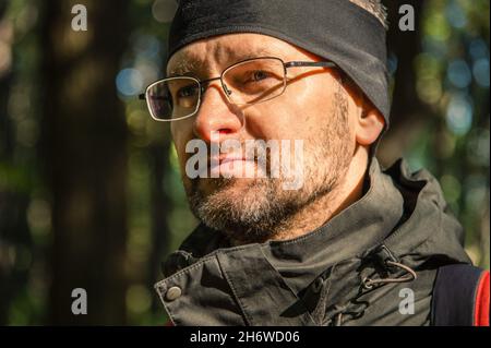 Außenportrait Nahaufnahme eines Mannes mittleren Alters in einem schwarzen Stirnband und Sport-Anorak mit Brille Stockfoto