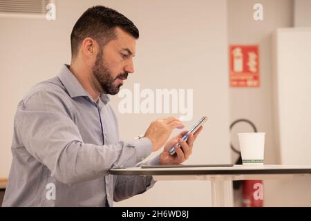 Junger attraktiver Geschäftsmann, der mit Tablet und Mobiltelefon arbeitet. Stockfoto