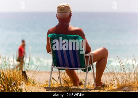Alter Mann Urlauber Liegestuhl am Strand, entspannende Zeit Rückansicht, Urlaub ruhiger Sommer Stockfoto
