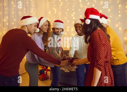 Glückliche männliche und weibliche Freunde klirren Gläser Wein während der Neujahrsfeier zu Hause. Stockfoto