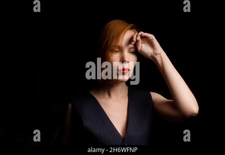 Eine Frau mittleren Alters in den Vierzigern im geistigen Niedergang, verärgert, nachdenklich auf schwarzem Hintergrund. Krisenkonzept. Stockfoto