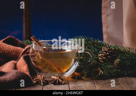 Tee in einer Glasschale auf einem rustikalen Holztisch an einem Fenster mit Sternenhimmel im Hintergrund Stockfoto