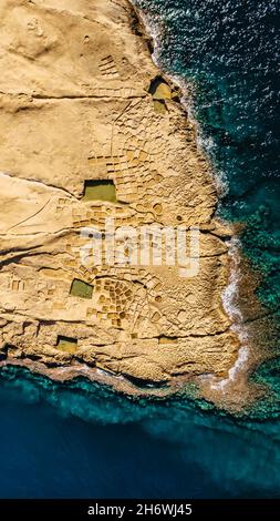 Luftaufnahme der Xwejni Salzpfannen, Xlendi Cliffs auf der Insel Gozo, Malta.erstaunliche natürliche Kreationen aus Kalkstein.traditionelle Meersalzproduktion.Mediterran Stockfoto