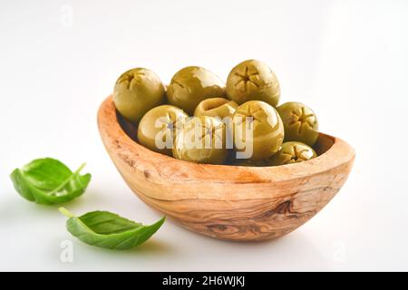 Köstliche grüne Oliven mit Rosmarinblättern in Holzschüssel, isoliert auf weißem Hintergrund. Stockfoto